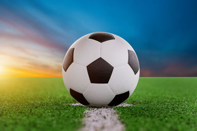 Digital composite of soccer ball on playing field against sky 