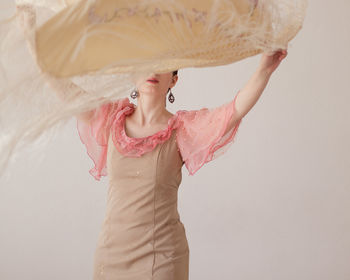 Young woman looking away while standing against wall