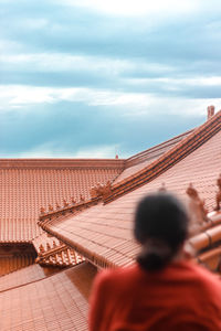A young girl gazing out at the buddist temple and terracotta roofs.