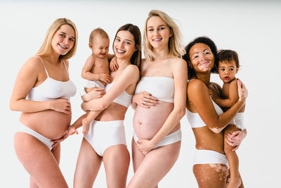 Portrait of young woman in bikini while standing against white background