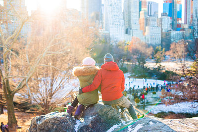 Rear view of people on rock in city during winter