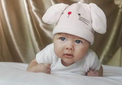 Close-up of cute baby girl wearing bunny hat while lying on bed