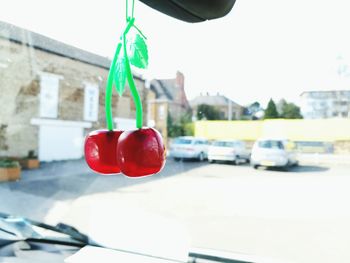 Close-up of red hanging from car against sky