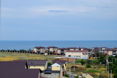 Houses by sea against sky in city