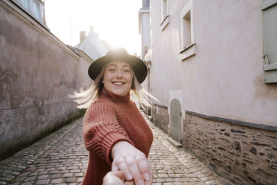 Portrait of woman holding hand in alley