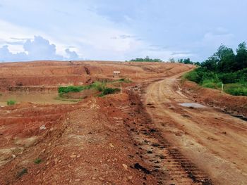 Dirt road passing through landscape against sky