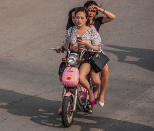 Full length of woman riding bicycle on road in city