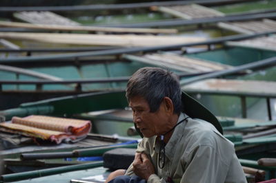 Senior man sitting against nautical vessels