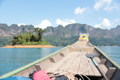 Boat sailing on lake by mountains against sky