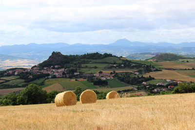 Hay bales on field against sky