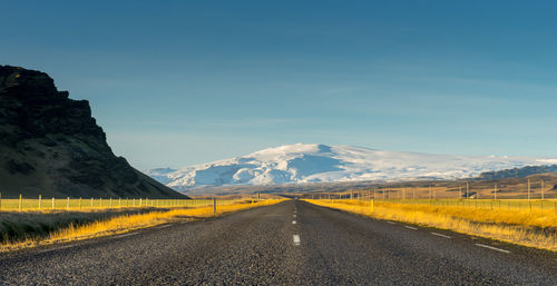 Scenic view of road by mountains against sky