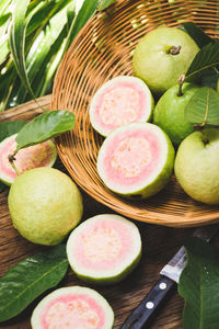 High angle view of fruits and leaves in basket on table