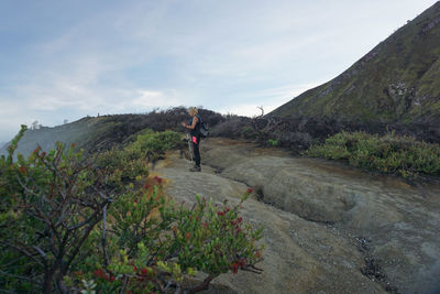 Side view of woman hiking on mountain against sky