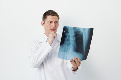 Female doctor holding mobile phone against white background