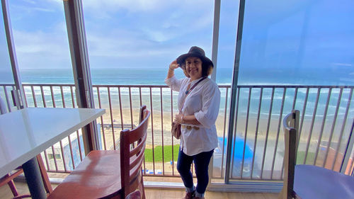 Full length of young woman standing against sea