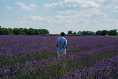 Rear view of man standing on field against sky