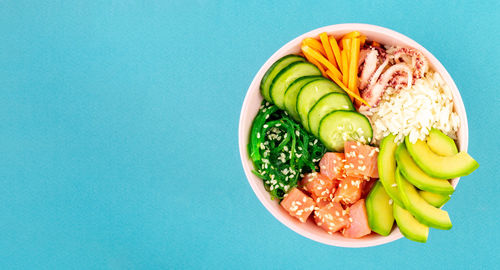 Directly above shot of chopped fruits in bowl against blue background