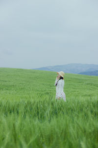 Rear view of woman standing on grassy field against clear sky