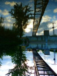 Reflection of trees on bridge against sky