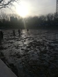 Silhouette people on frozen lake against sky during winter