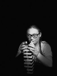 Portrait of young woman drinking against black background