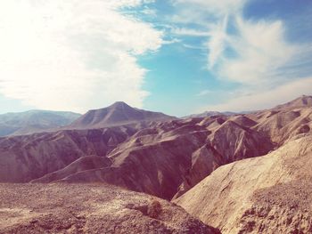 Scenic view of mountains against cloudy blue sky on sunny day