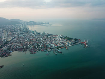 High angle view of city by sea against sky