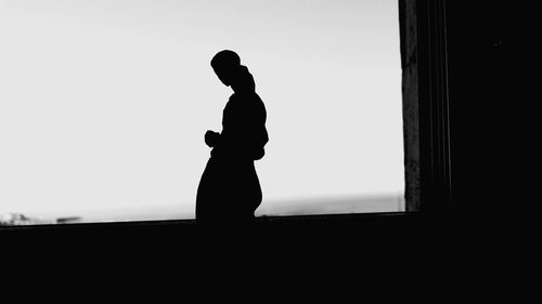 Side view of silhouette woman standing against clear sky