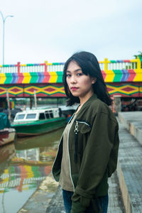 Portrait of beautiful young woman standing against sky