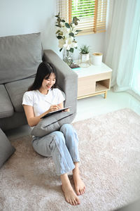 Young woman using laptop while sitting on sofa at home