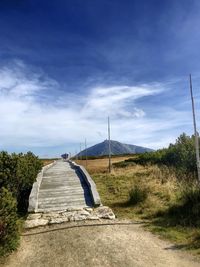 Road amidst field against sky