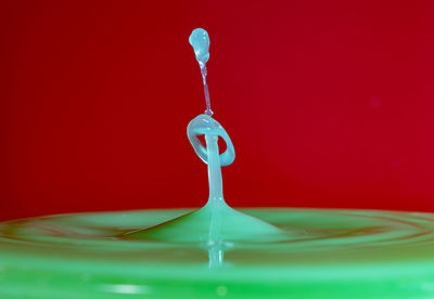 Close-up of water drop on glass against red background