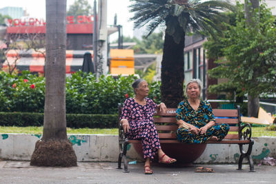 People sitting on bench against trees