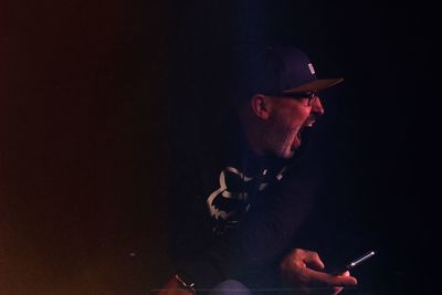 Man shouting while holding equipment against black background