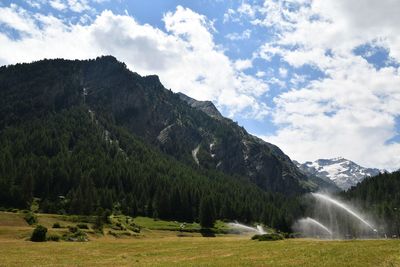 Hay field with irrigation system and mountains in the background, lillaz, aosta, italy