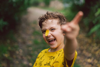 Portrait of a boy with a yellow leaf on his nose. autumn mood.