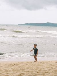 Full length of man standing on beach against sky