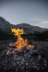 Bonfire on rock by land against sky