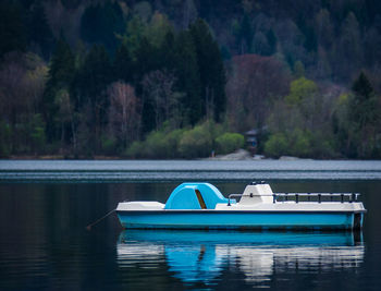 Boat moored on lake by trees