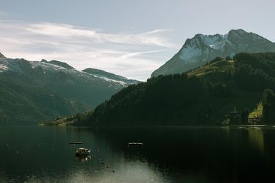 Scenic view of lake by mountains against sky