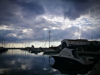 Sailboats moored at harbor against sky