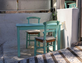 Empty chairs and table against wall