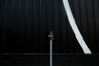 Low angle view of a handicap parking sign in front of a dark building