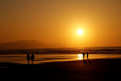 Silhouette people at beach during sunset