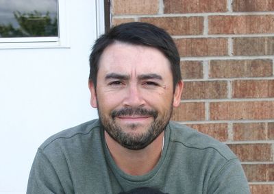 Close-up portrait of man against brick wall at home