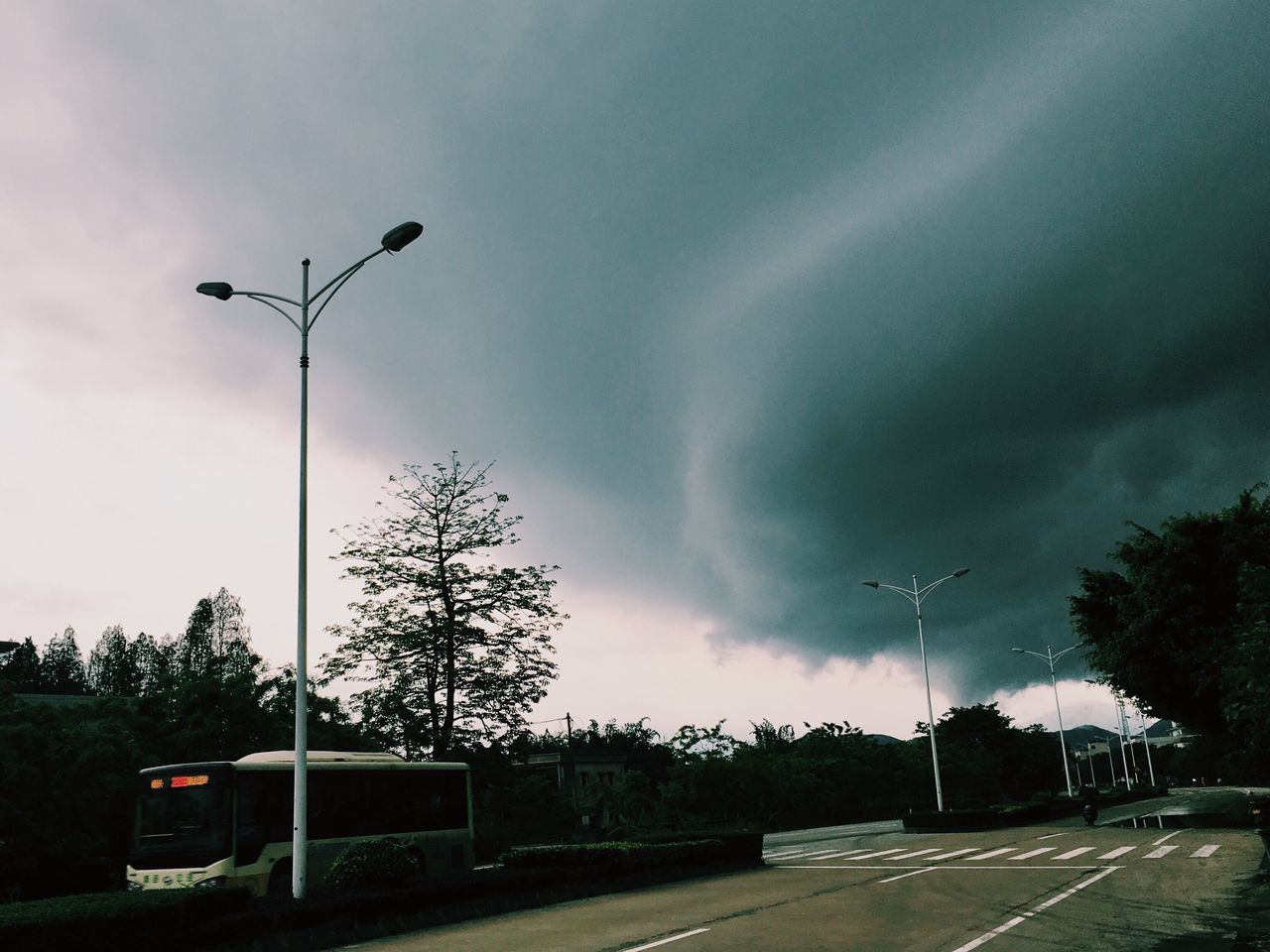 LOW ANGLE VIEW OF STREET LIGHTS AGAINST DRAMATIC SKY