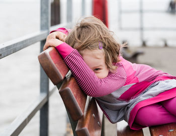 Portrait of cute playful girl sitting on bench