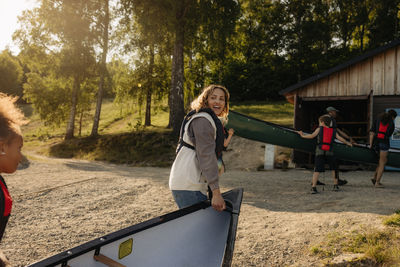 Counselor assisting kids carrying kayak at summer camp