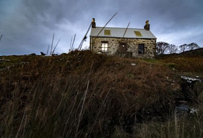 Low angle view of old house on field against sky