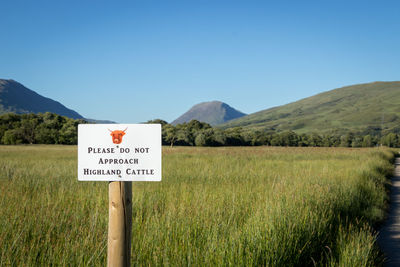 Information sign on field against sky